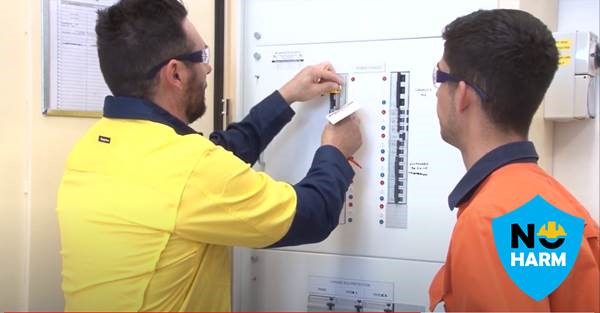 two electrical workers at a board