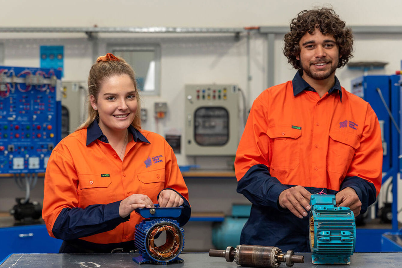 Male and female electrical apprentices smiling and working together