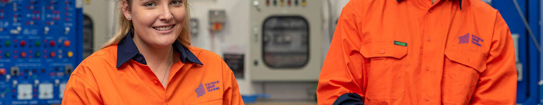 Male and female electrical apprentices smiling and working together